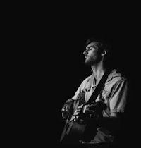 a black and white photo of a man playing an acoustic guitar