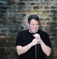 a man holding a microphone in front of a brick wall