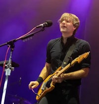 a man playing an electric guitar in front of a microphone