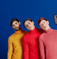 three men in colorful sweaters standing in front of a blue background