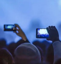 a group of people taking pictures with their cell phones at a concert